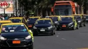 Vários táxis pretos com teto amarelo circulando por uma avenida movimentada em Santiago do Chile.