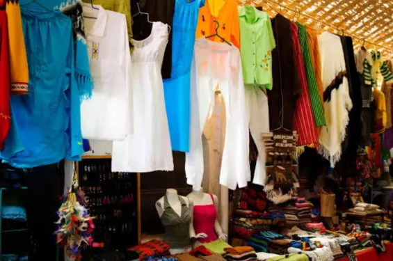 Roupas tradicionais e artesanatos pendurados em uma barraca de mercado em San Pedro de Atacama, exibindo uma variedade de cores e estilos típicos da região.