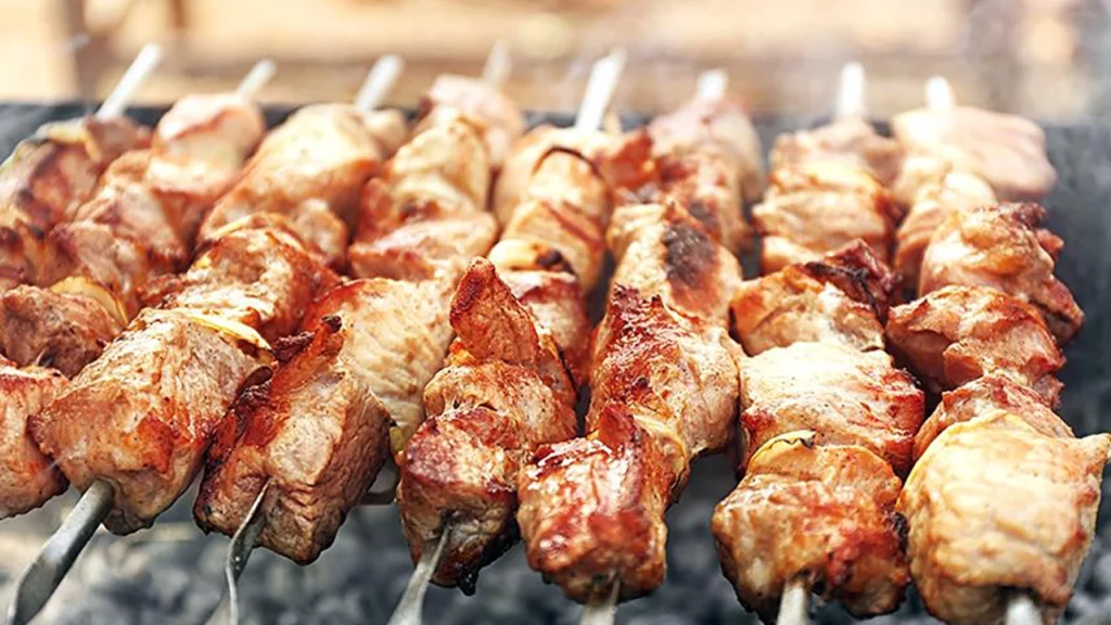 Espetinhos de carne grelhados sobre brasas, com pedaços suculentos e bem temperados.