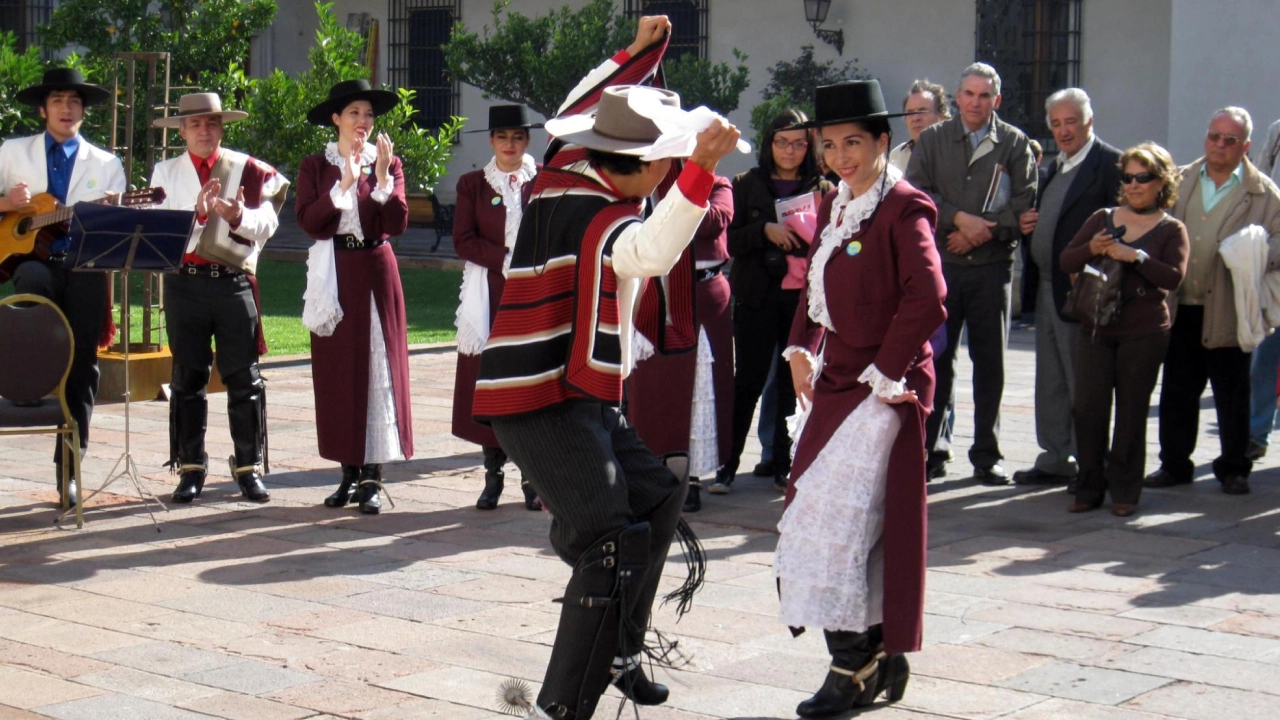 Grupo de pessoas assistindo a uma apresentação de dança tradicional chilena, conhecida como 'cueca', durante as Fiestas Patrias.