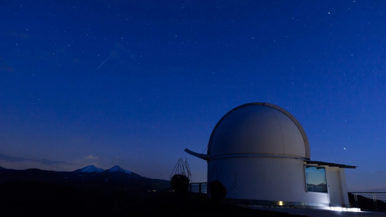 Cúpula de observatório astronômico sob um céu estrelado, com montanhas ao fundo, em Las Condes, Santiago.