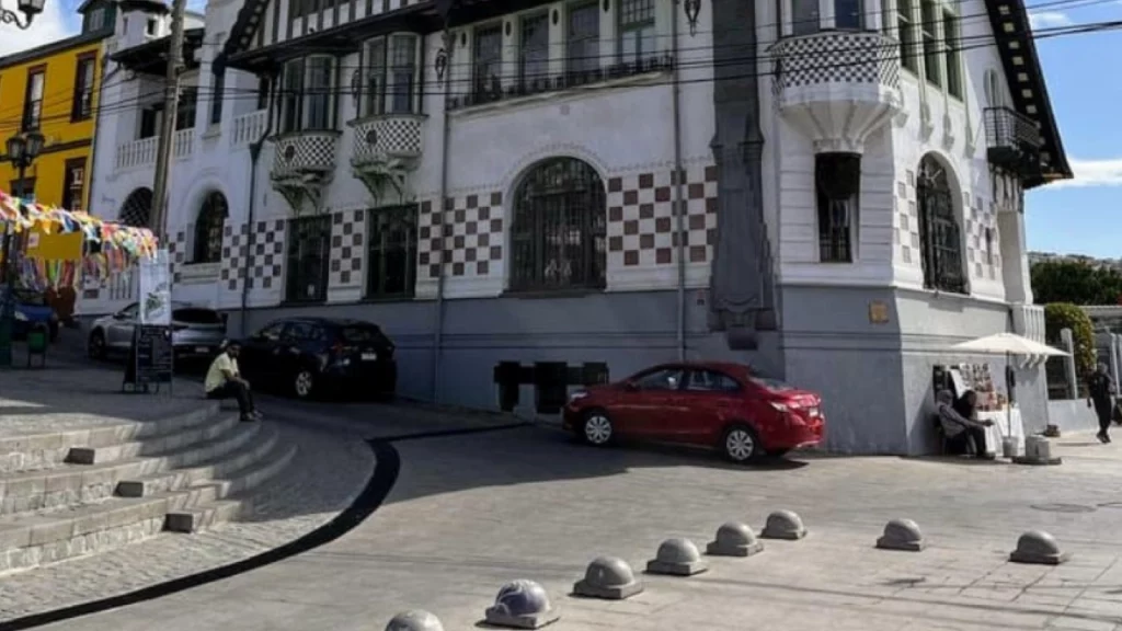 Fachada de um edifício histórico no Paseo Yugoslavo, com bandeirinhas coloridas decorando o ambiente e pessoas aproveitando o dia ensolarado