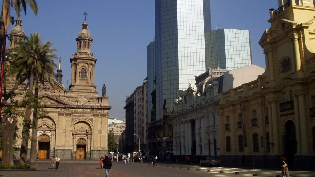 Praça de Armas em Santiago, Chile, com a Catedral Metropolitana e edifícios históricos ao redor, combinando arquitetura colonial e moderna.