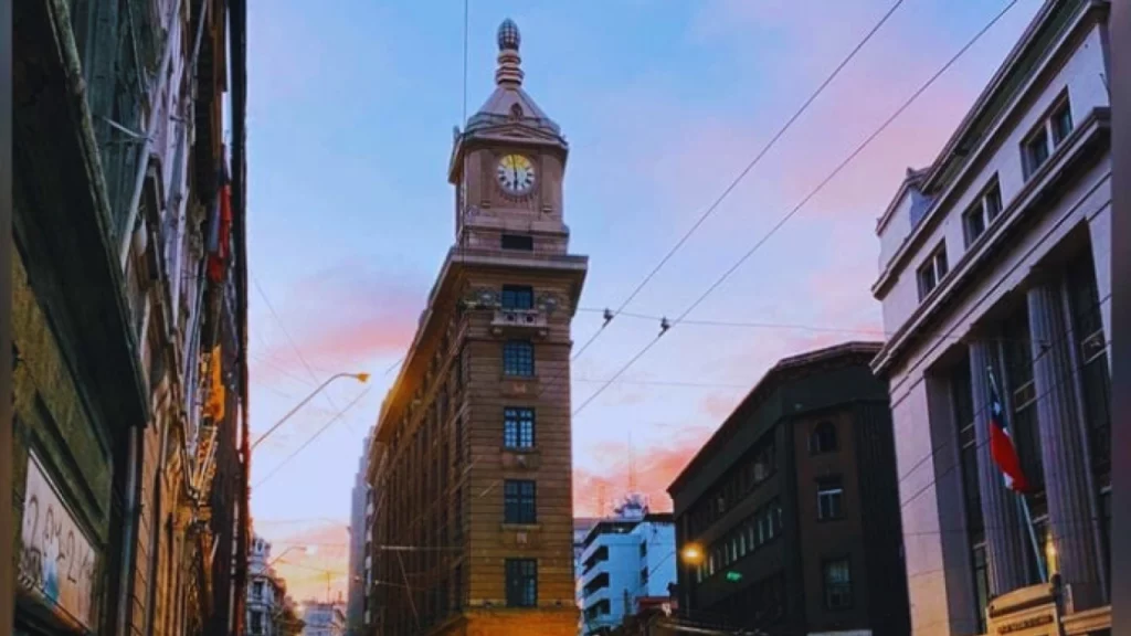 Torre do Relógio Turri ao pôr do sol, com céu colorido e edifícios históricos no centro de Valparaíso.