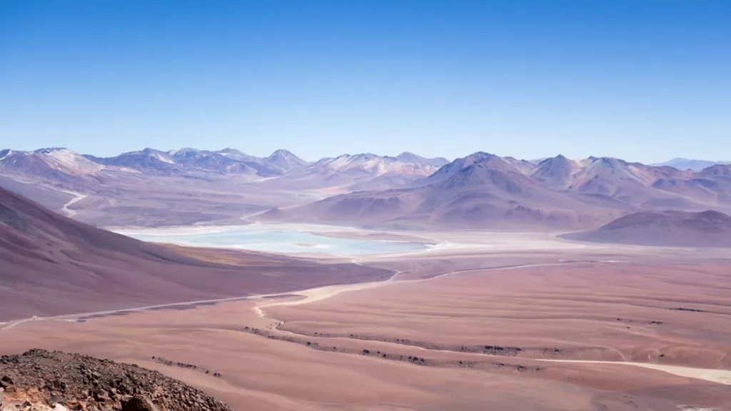 Vista deslumbrante do Deserto do Atacama, com paisagens áridas, montanhas ao fundo e um céu incrivelmente azul, ideal para aventuras e exploração.