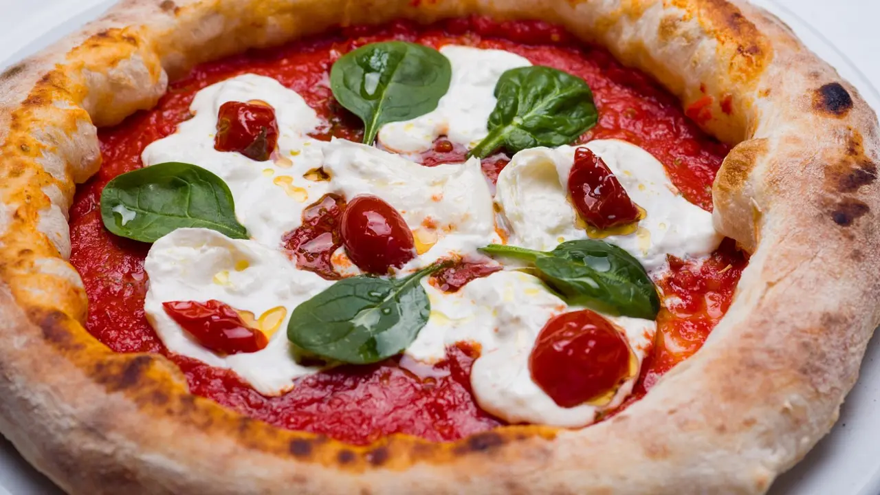 Pizza margherita com molho de tomate, queijo fresco e folhas de manjericão, servida em uma base crocante com borda levemente tostada.