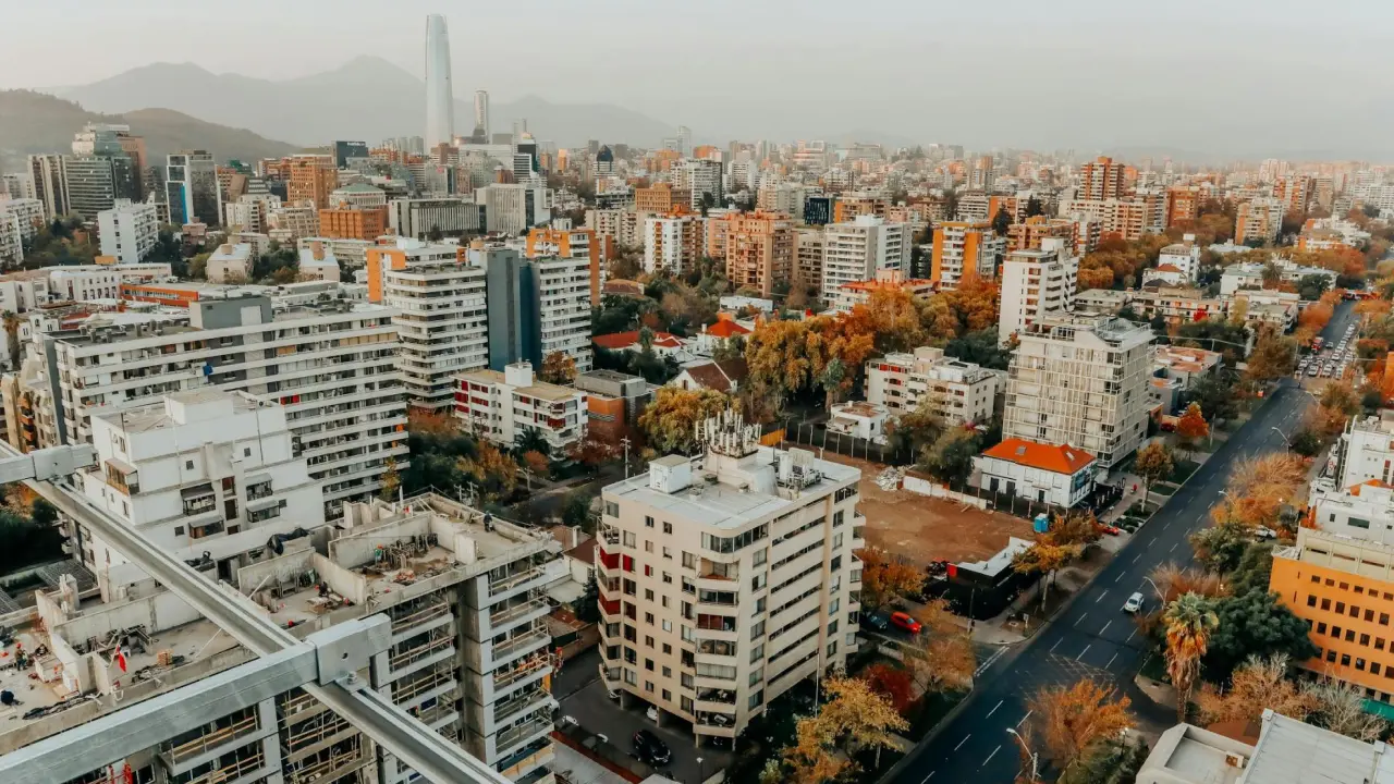 Panorama urbano de Santiago, Chile, mostrando edifícios altos e as montanhas ao fundo.
