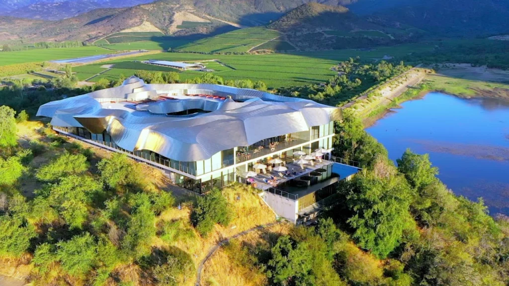 Vista aérea da moderna estrutura metálica da Vinícola VIK cercada por vinhedos e natureza.