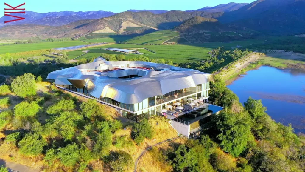 Vista aérea da moderna estrutura metálica da Vinícola VIK cercada por vinhedos e natureza.