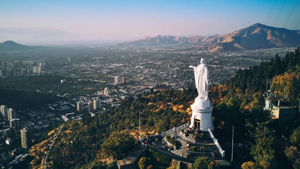 Vista aérea do Cerro San Cristóbal em Santiago, com a estátua da Virgem Maria e a cidade ao fundo.