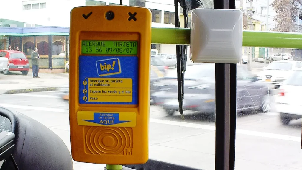 Validador de cartão Bip! instalado em um ônibus de transporte público em Santiago, com rua e prédios visíveis pela janela.