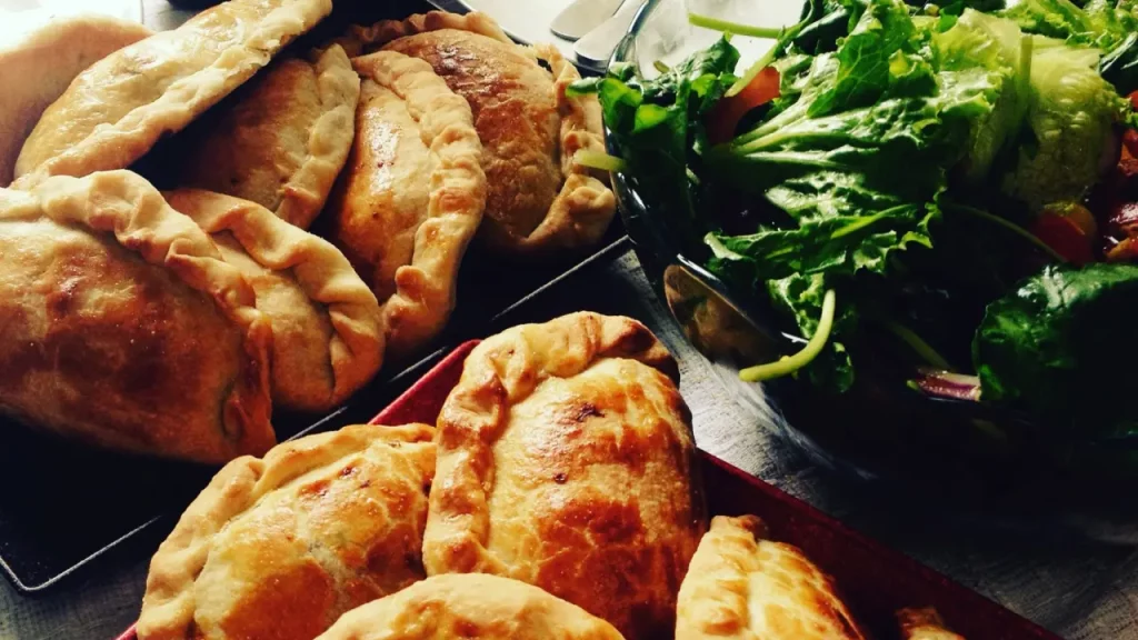 Empanadas douradas acompanhadas de salada verde e ají chileno — refeição tradicional da comida típica do Atacama.