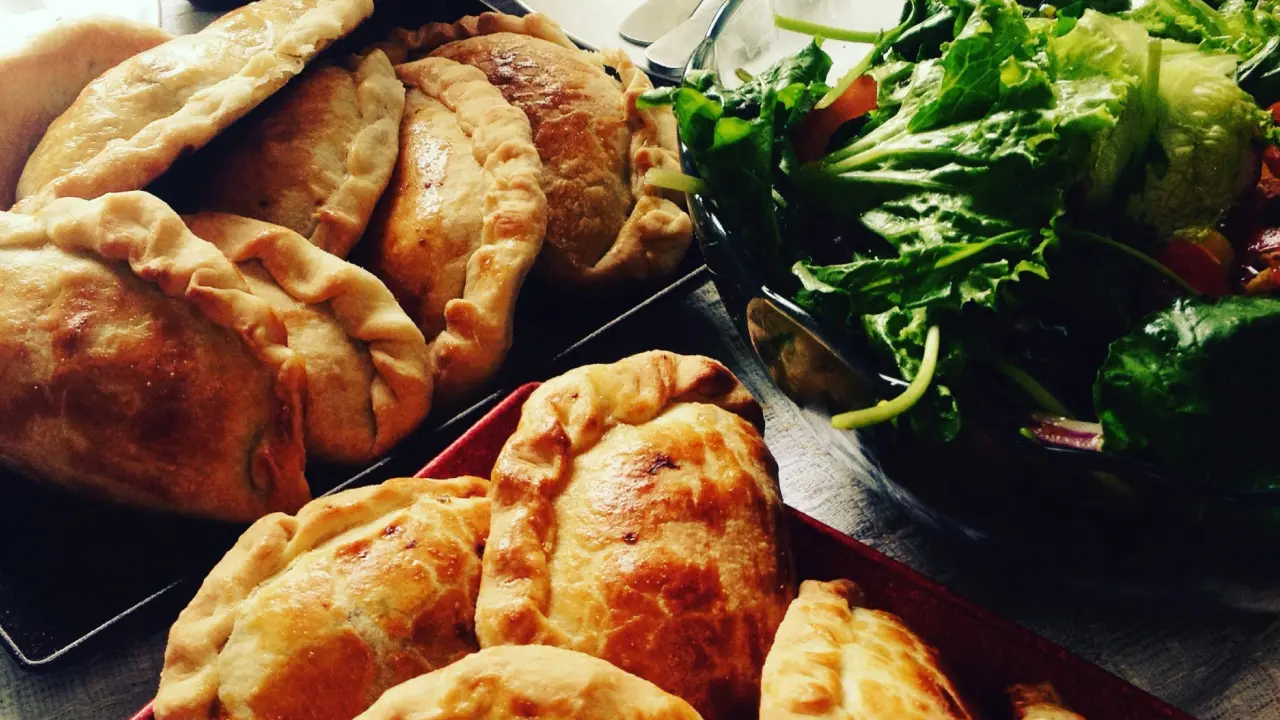 Empanadas douradas acompanhadas de salada verde e ají chileno — refeição tradicional da comida típica do Atacama.