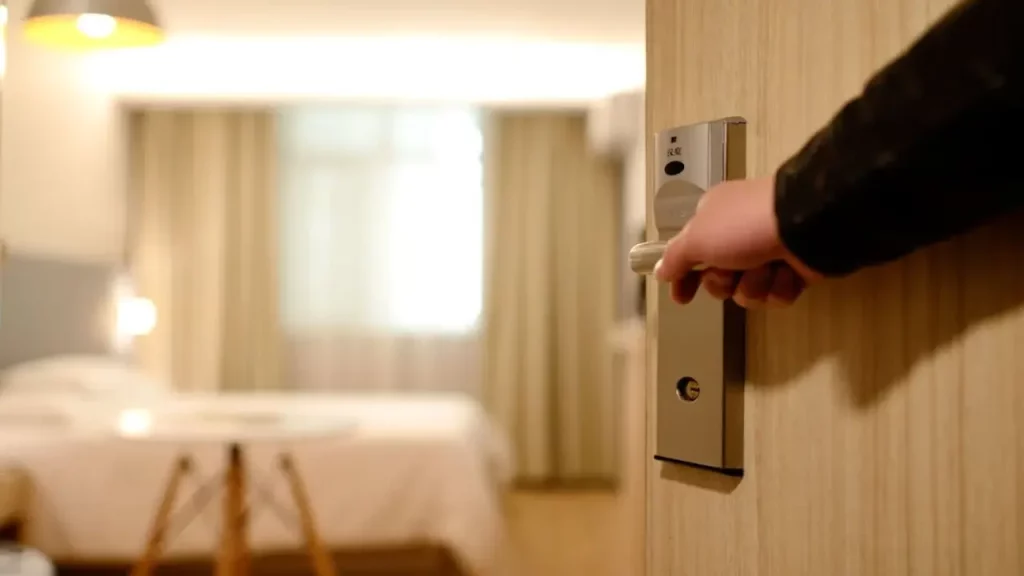 Pessoa abrindo a porta de um quarto de hotel moderno e aconchegante.