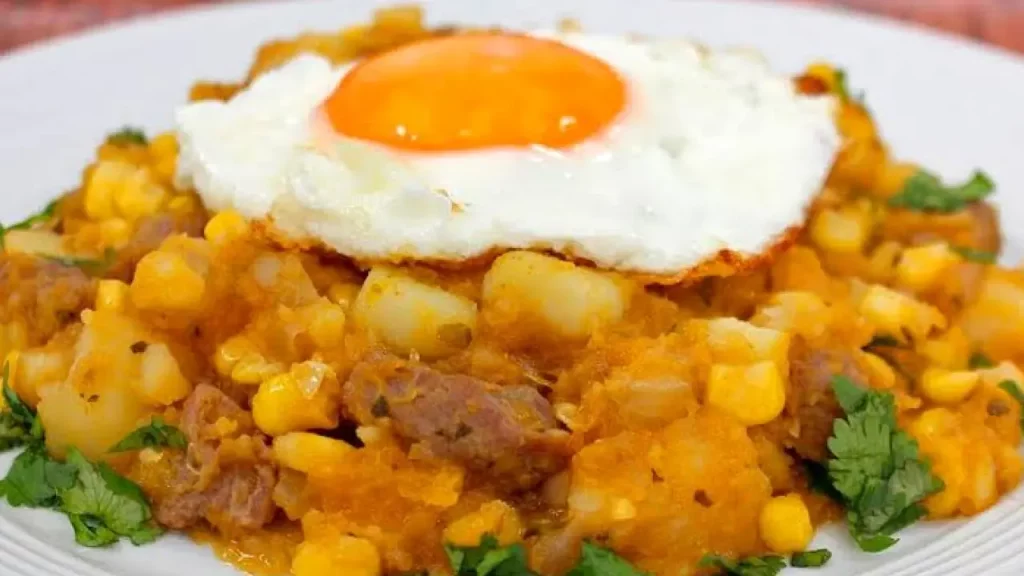 Prato de charquicán com batata, milho, carne e ovo frito servido em um prato branco — exemplo de comida típica do Atacama.