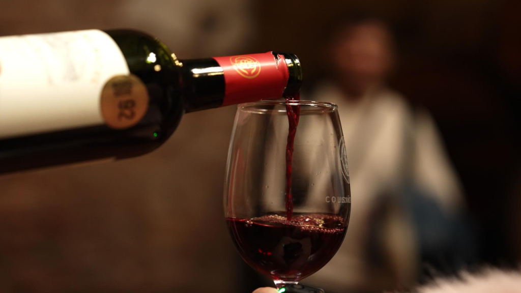 Vinho tinto sendo servido em taça durante degustação em vinícola no Chile.