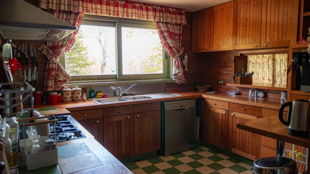 Cozinha rústica e aconchegante da Casa Condor, equipada com armários de madeira, fogão moderno, lava-louças e vista para a natureza.